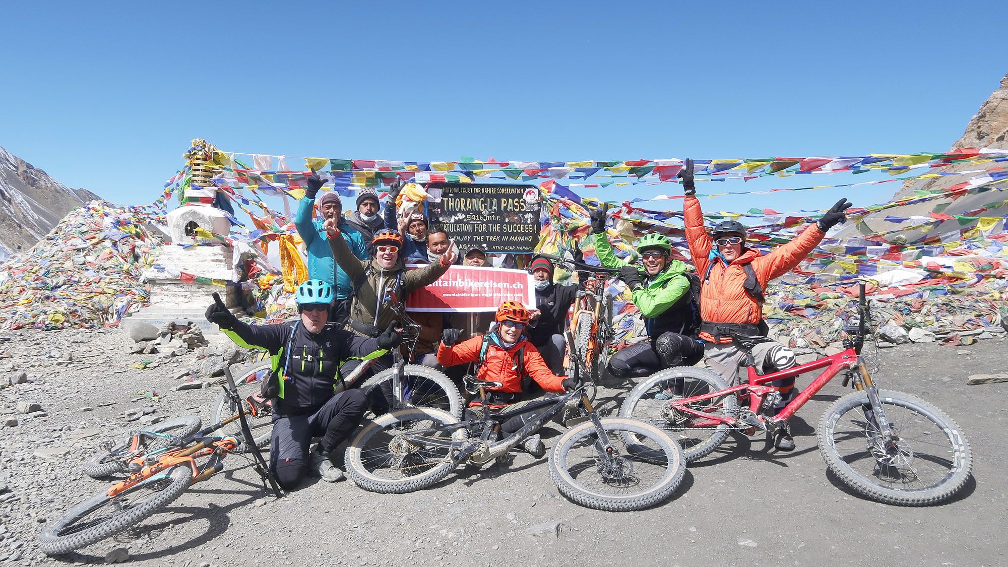 Gruppe Mountainbiker aufm dem höchsten Punkt des Thorong La Pass.