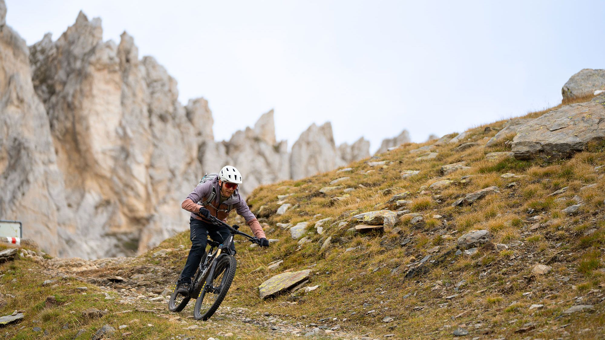 EIn Mountainbiker auf einem Trail vor einer Felsformation.