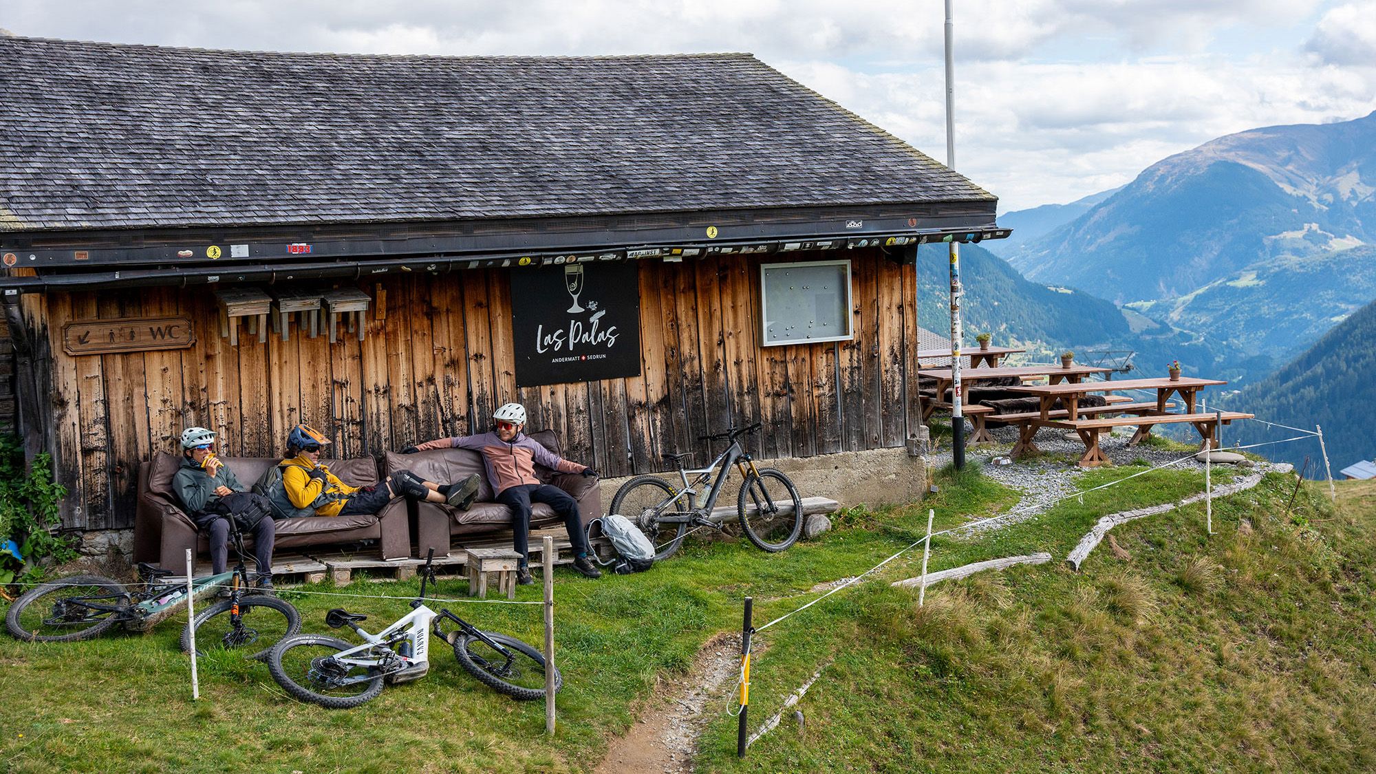Mountainbiker machen eine Pause vor einer Hütte.
