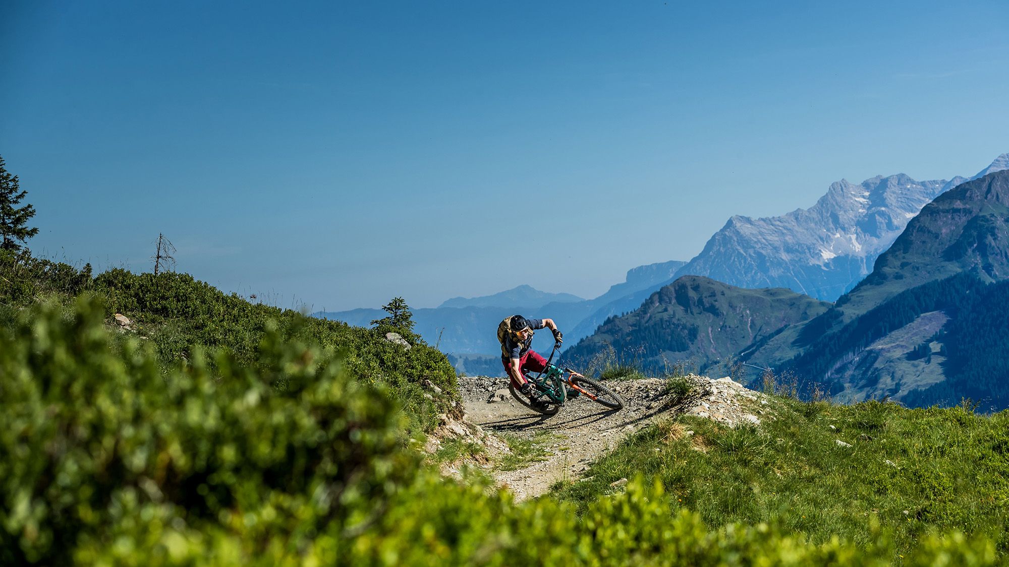 Ein Mountianbiker auf einem Trail mit Bergpanorama.