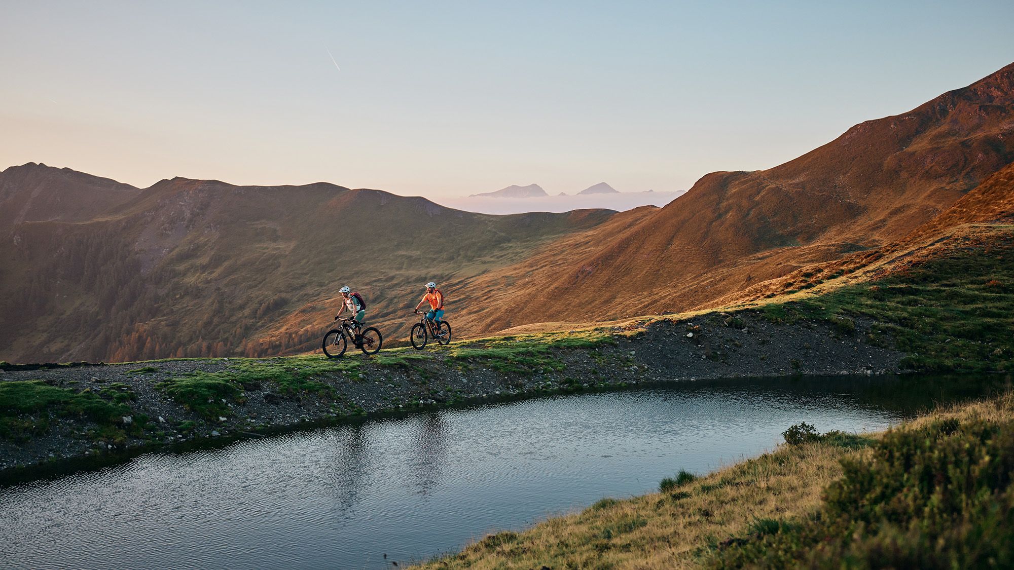 Zwei Mountainbiker vor einem Bergpanorama.